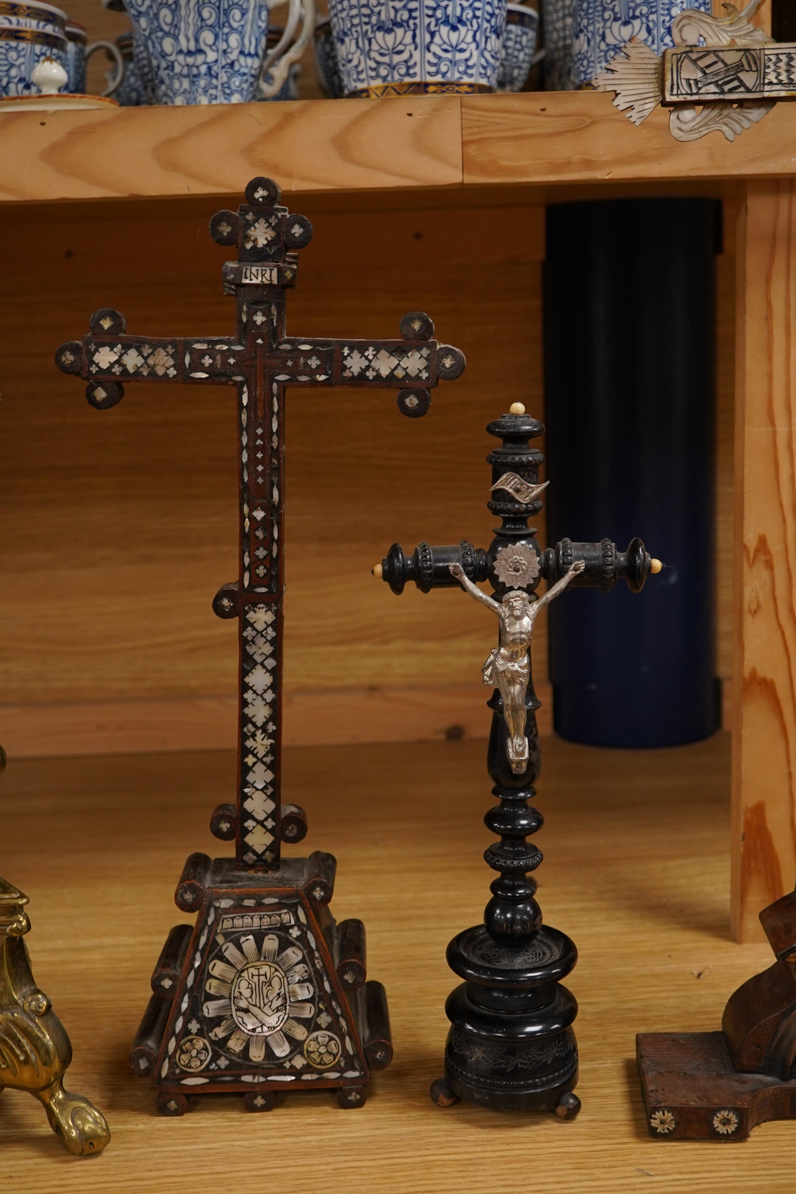 Two 19th century walnut and mother-of-pearl inlaid crucifixes and a German ebonised and white and metal mounted crucifix and a pair of Dutch or German brass tripod base cricket candlesticks, largest 56cm high (5)